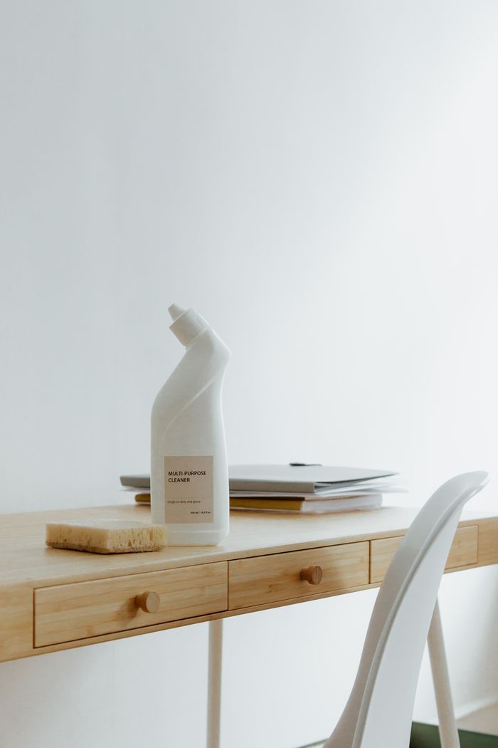 A tidy, well-arranged home office desk featuring a cleaning bottle and sponge, highlighting simplicity and practical use.