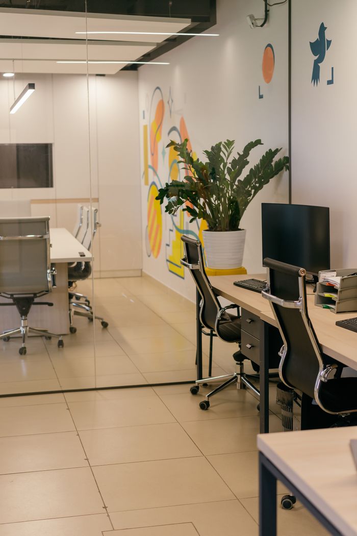 A roomy, modern office interior with glass dividers, elegant furnishings, and colorful wall artwork.